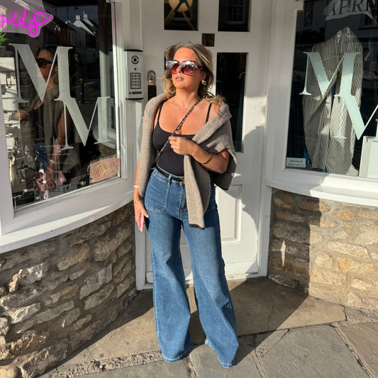 Person standing in front of a store entrance with a reflective surface.